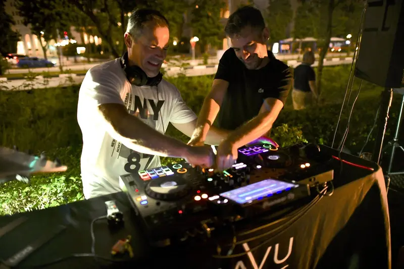 Two DJs playing back to back in a garden at dusk
