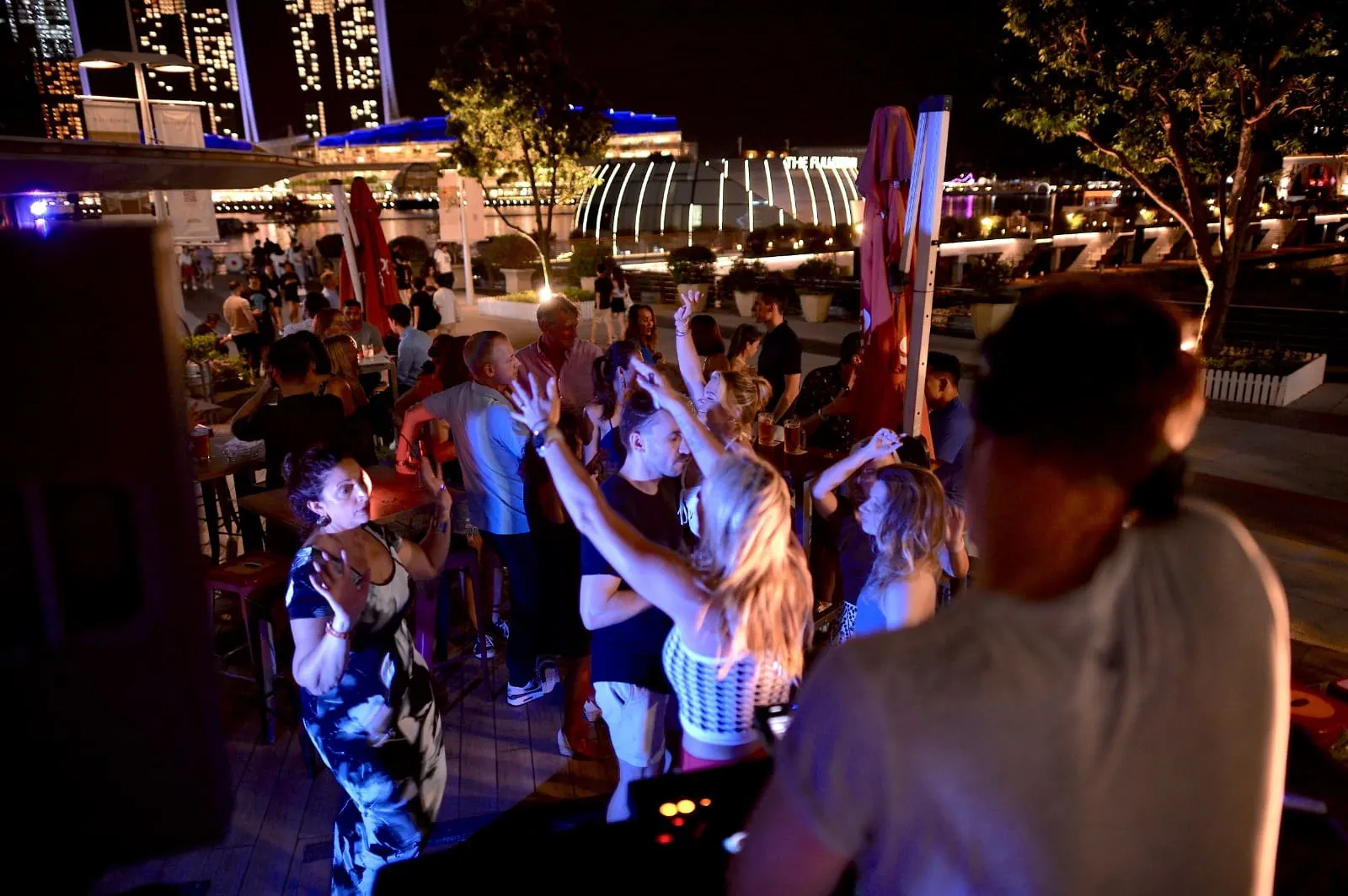 Guests dancing under blue lights at a waterfront night event
