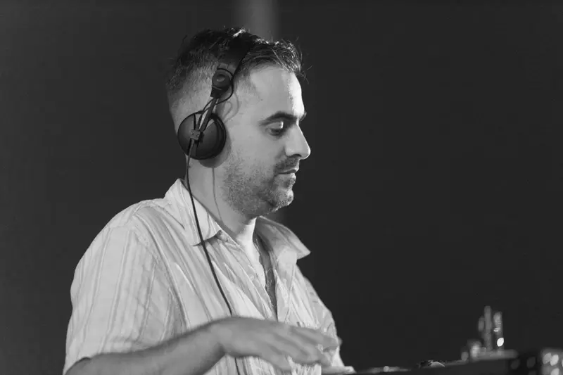 Black and white shot of a DJ with headphones mixing a set