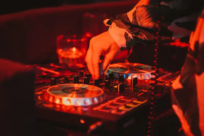 DJ hands on a controller lit in deep red