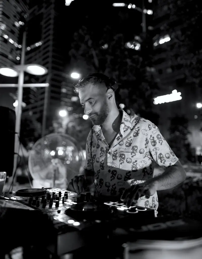 Driguo mixing a night set in black and white with city towers behind the booth