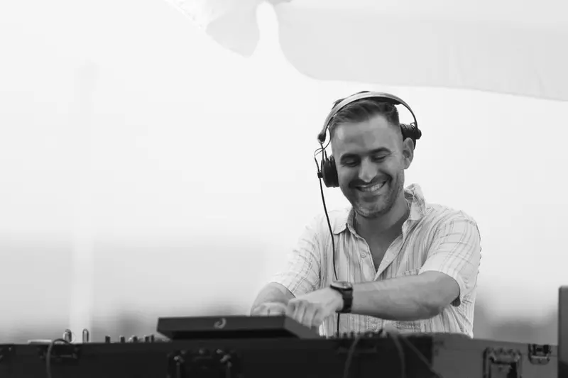Black and white photo of Driguo smiling behind the decks