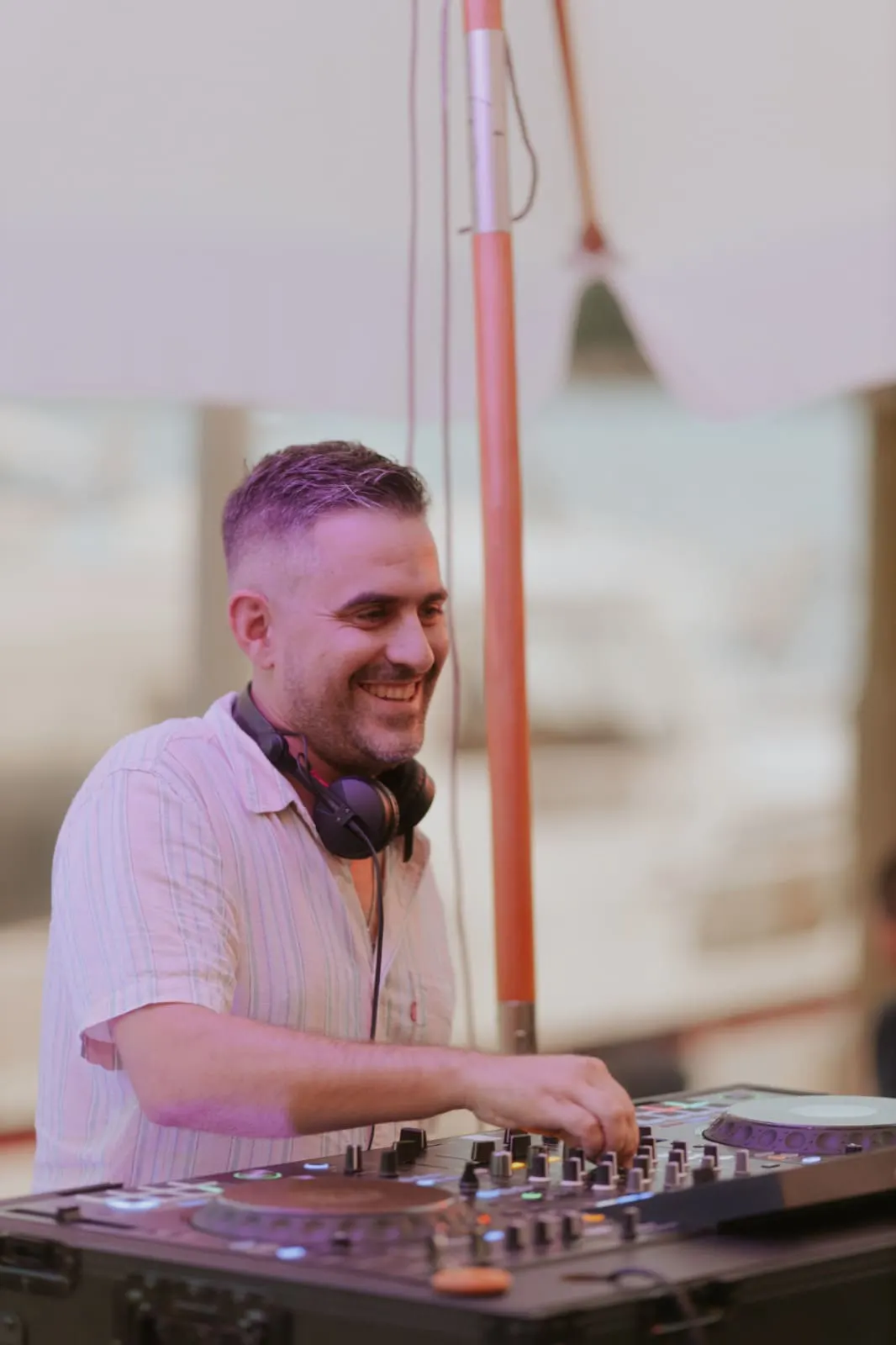 Driguo with headphones around his neck, hands on the mixer