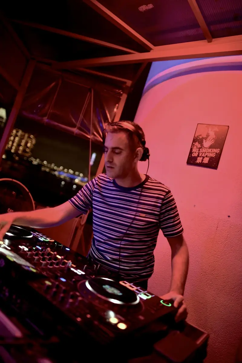 Driguo mixing in a club booth washed in red light