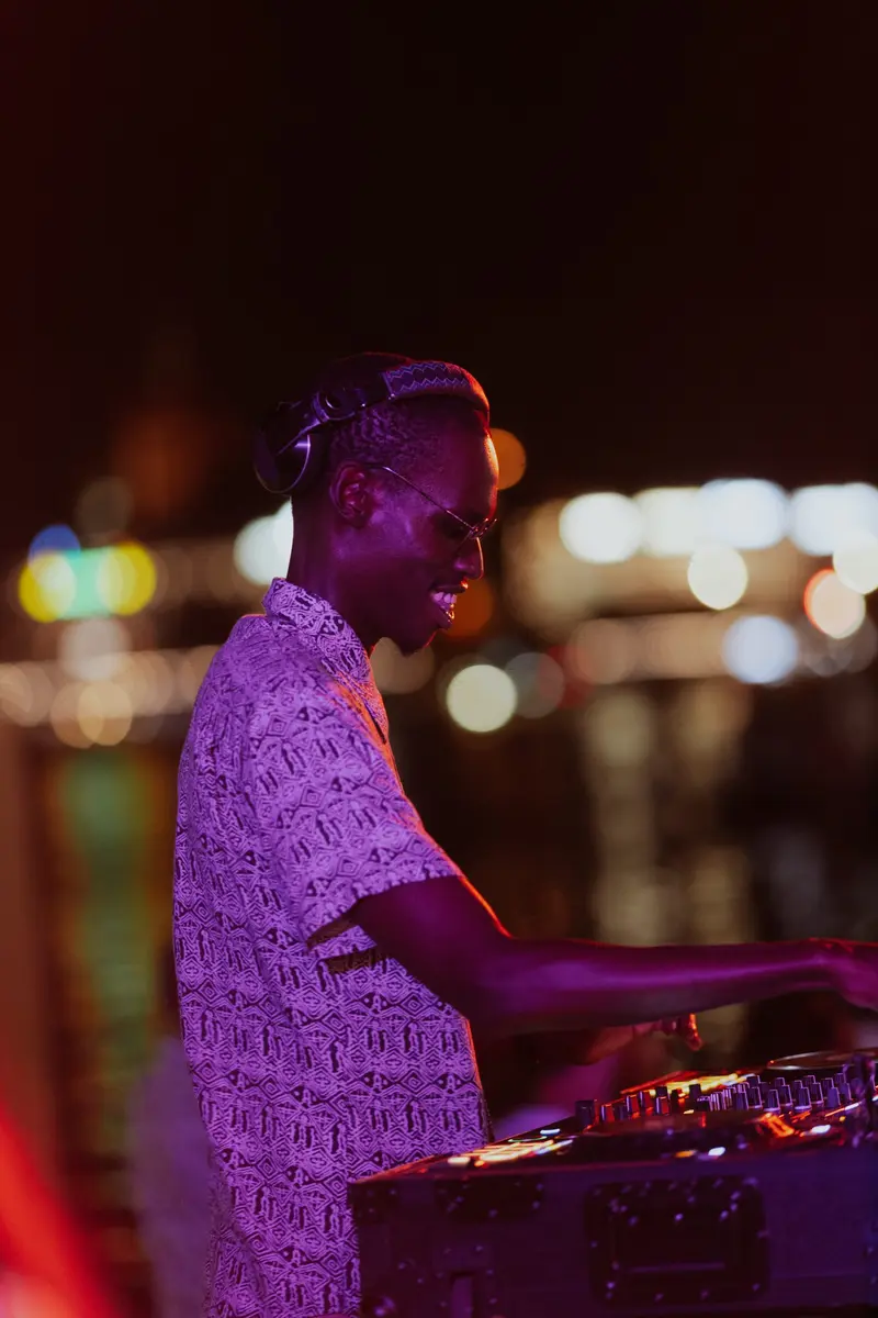 A guest DJ leaning over the mixer under evening lights
