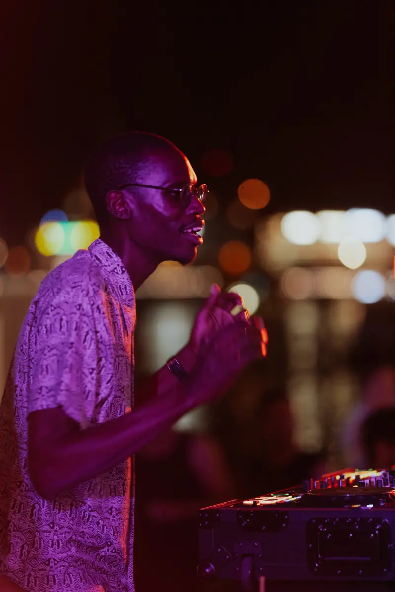 A guest DJ in a pink shirt playing against night bokeh
