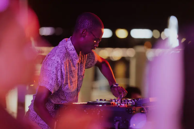 A guest DJ in a pink shirt working the mixer