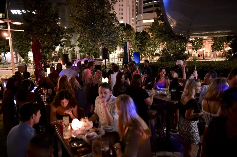 Glowing table lamps and a lively crowd on an evening terrace