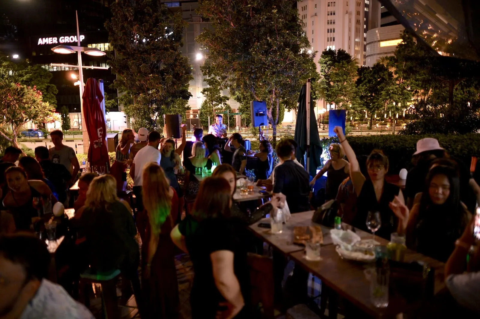 A full waterfront terrace crowd gathered around tables at night